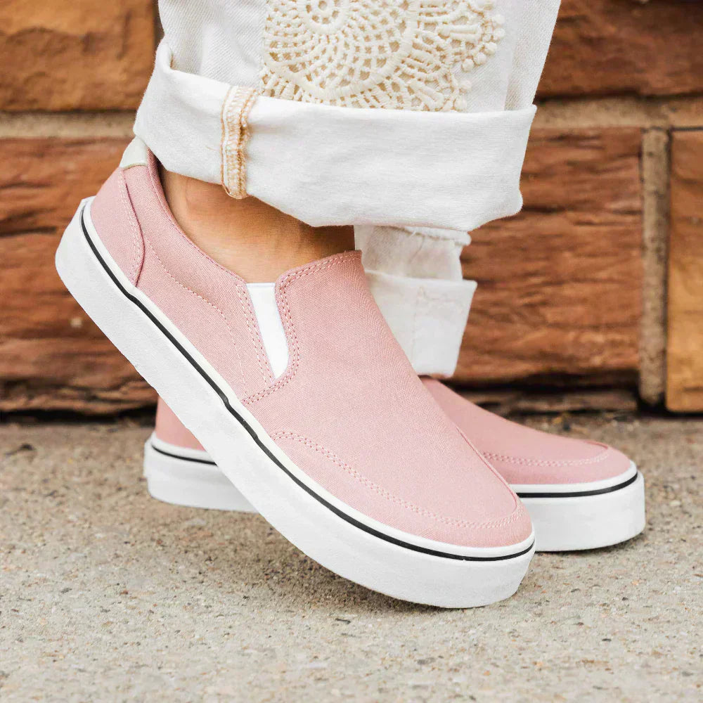 A woman in white trousers wearing Splay STREETSTYLE Slip-On Azalea shoes, standing casually outdoors.