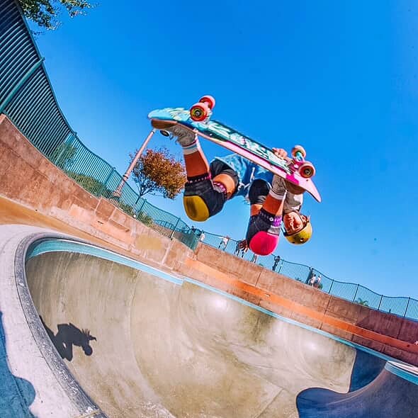 A girl wearing Splay skate shoes while riding a skateboard.