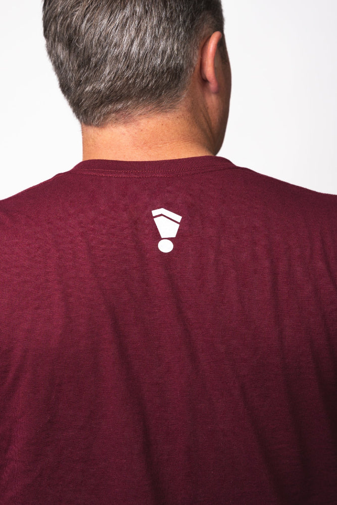 Maroon t-shirt with a white logo on the back, worn by a person.