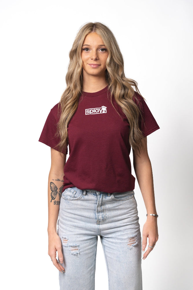Woman wearing a maroon t-shirt with a logo and light blue jeans on a white background