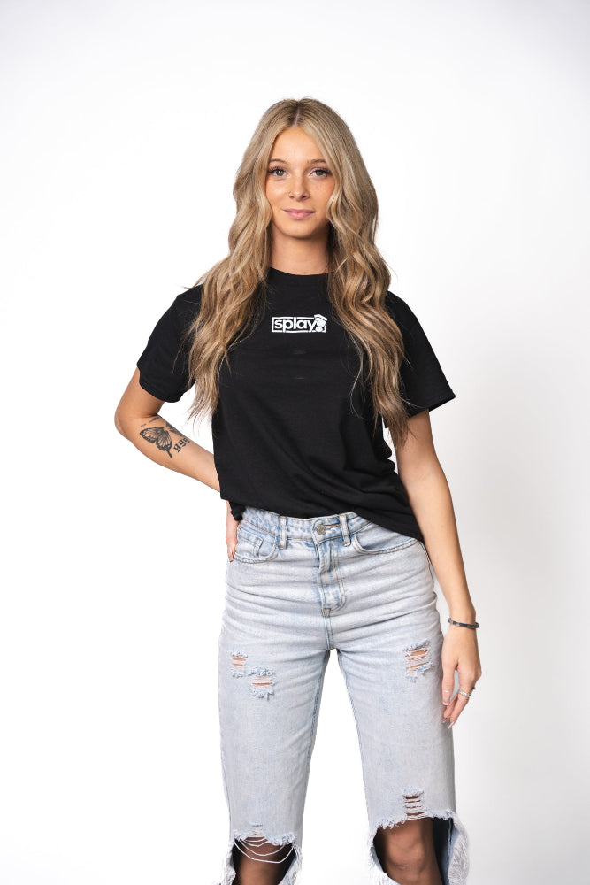 Woman wearing a black t-shirt with a logo and light blue jeans on a white background