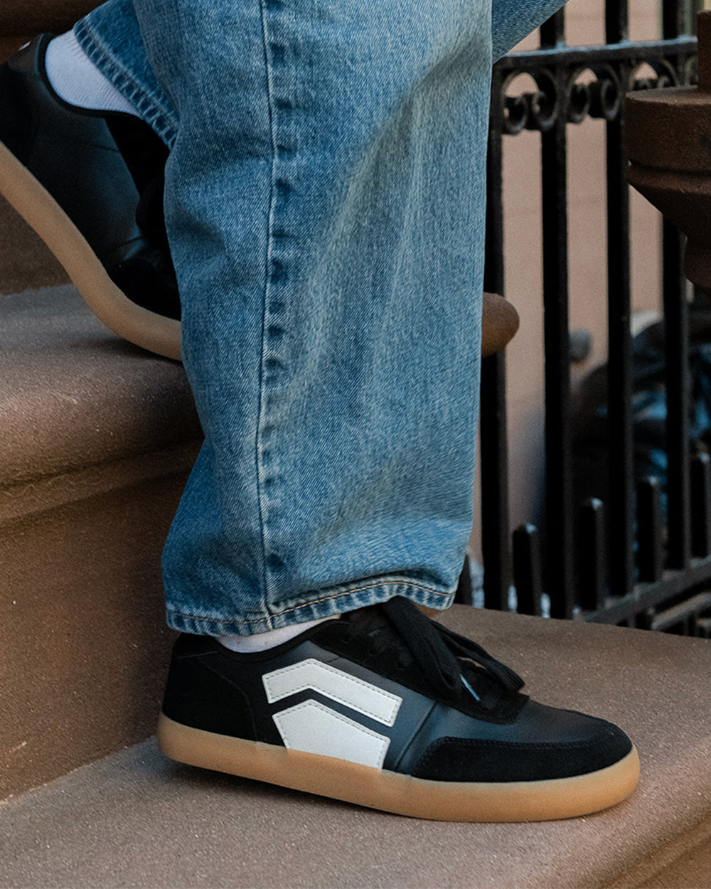 Splay 101 Blackboard '26 barefoot shoes — low-top court sneaker with a side stripe and gum sole, lifestyle photo, the shoes shown in use outdoors