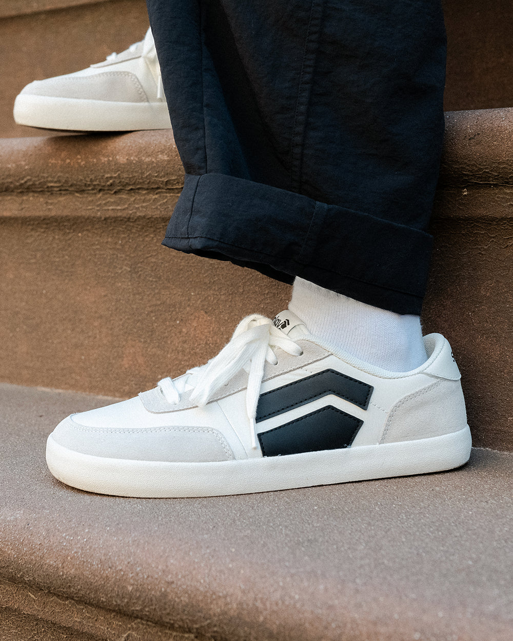 Splay 101 Graphite '26 barefoot shoes — low-top court sneaker with a side stripe and gum sole, lifestyle photo, the shoes shown in use outdoors